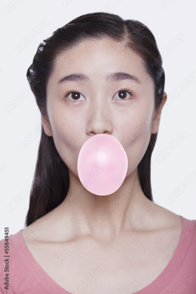 Young playful woman blowing a bubble out of bubble gum, studio shot Young playful woman blowing a bubble out of bubble gum, studio shot