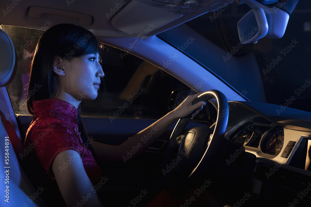 Young beautiful woman in a traditional Chinese dress driving at night  