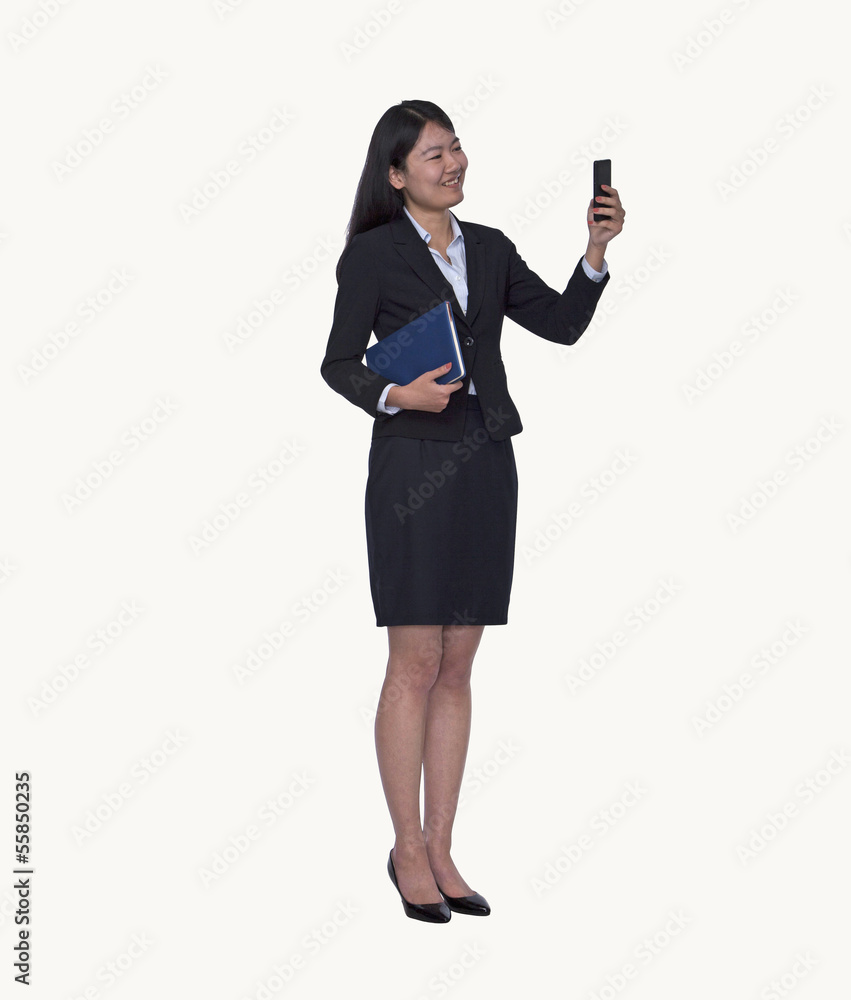 Smiling young businesswoman looking at her phone, full length, studio shot Smiling young businesswoman looking at her phone, full length, studio shot