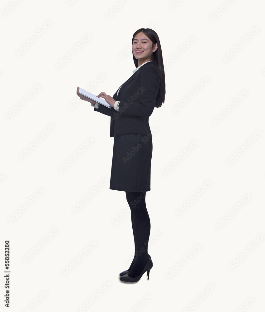 Portrait of young businesswoman holding a digital tablet, looking at camera, full length, studio shot