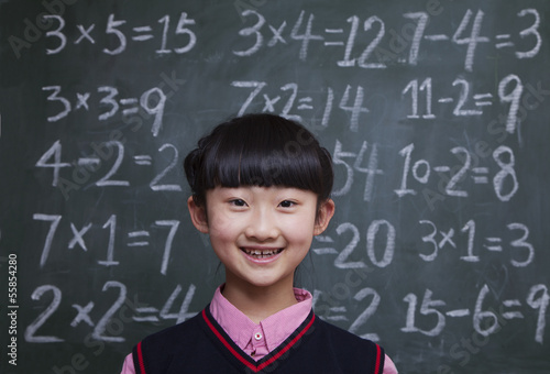 Portrait of schoolgirl in front of blackboard with math equations