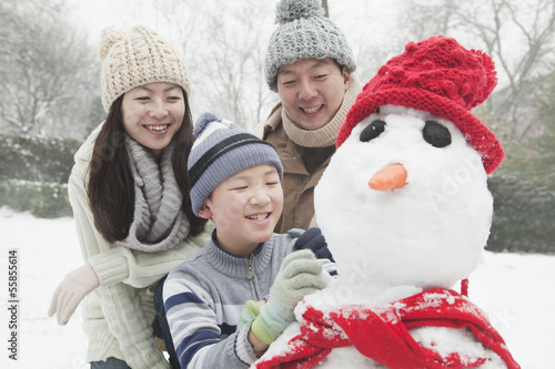 Family making snowman in a park in winter