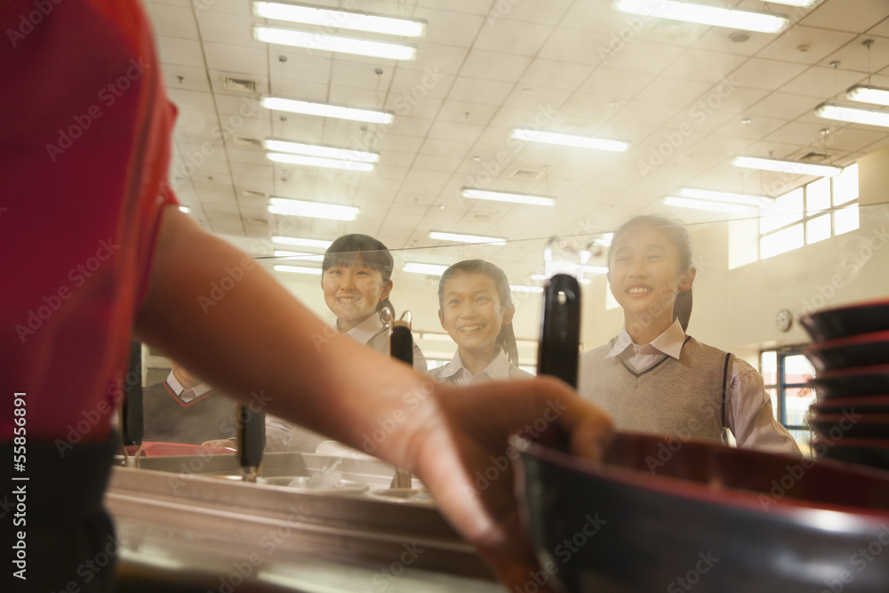 School cafeteria worker serves noodles to students School cafeteria worker serves noodles to students