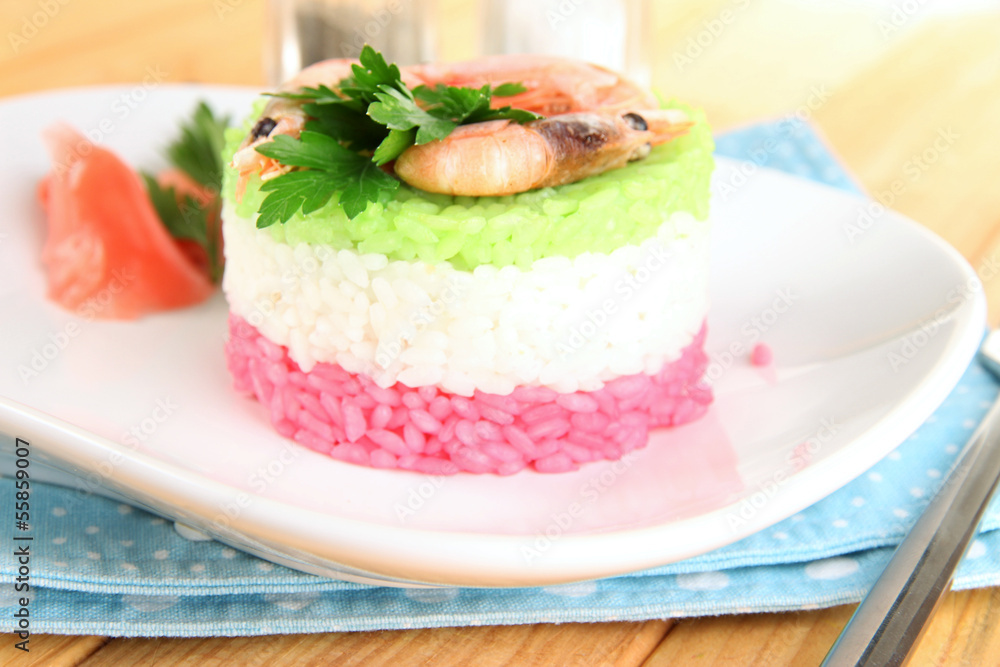 Colored rice on plate on napkin on wooden table