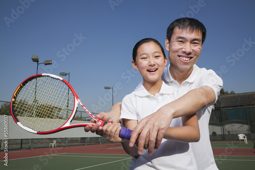 Young girl playing tennis with her coach 