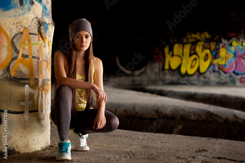 Teenage girl with gray hat in front of graffiti wall