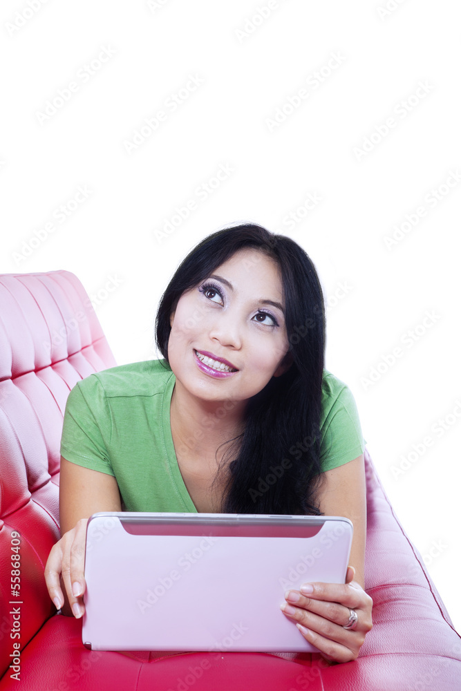 Beautiful female on red sofa using e-tablet, isolated Beautiful female on red sofa using e-tablet, isolated