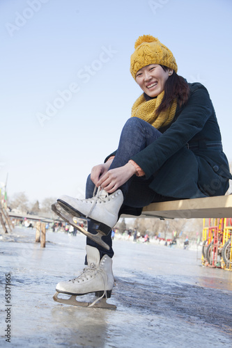 Young Woman Tying Ice Skates Outside