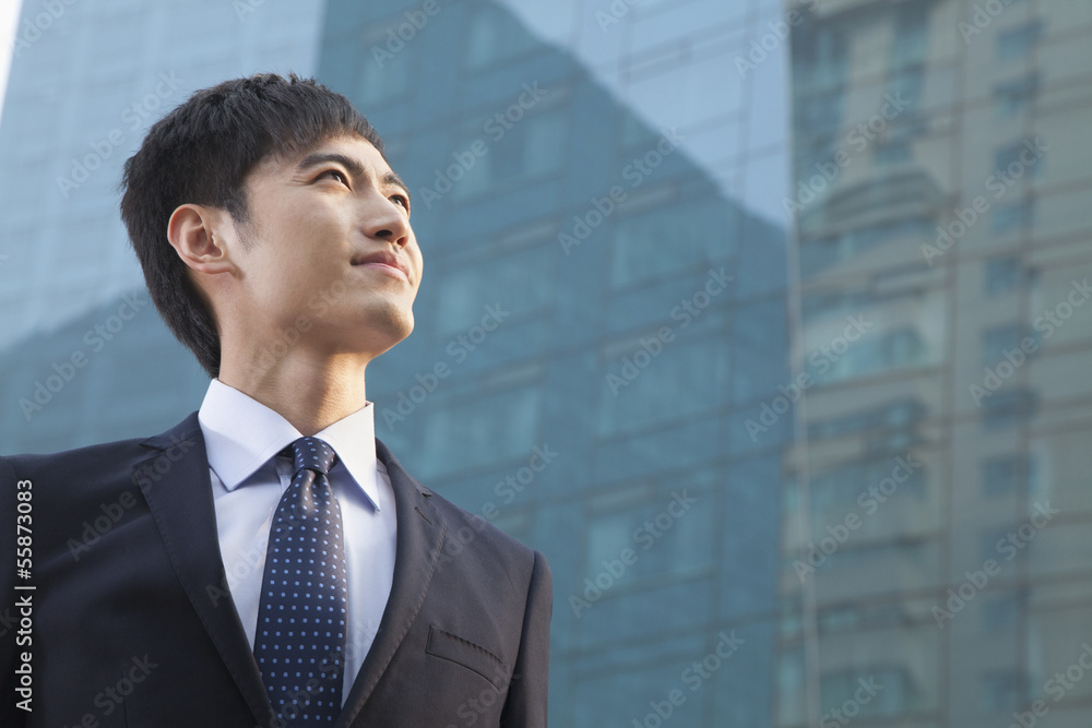 Young Businessman Looking Up, Glass Building, Portrait
