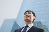 Portrait of young smiling businessman outside glass building