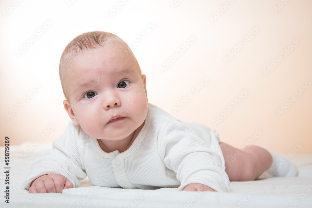 curious little baby lying on the blanket, orange background