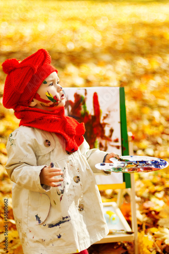 Child drawing on easel in Autumn Park. Creative kids development