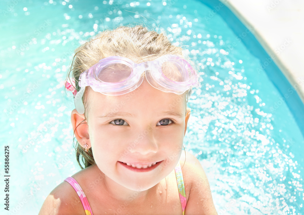 Naklejka premium Cute little girl in swimming pool in glasses