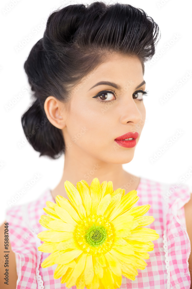 Thoughtful black hair model holding a flower and looking at came Thoughtful black hair model holding a flower and looking at came