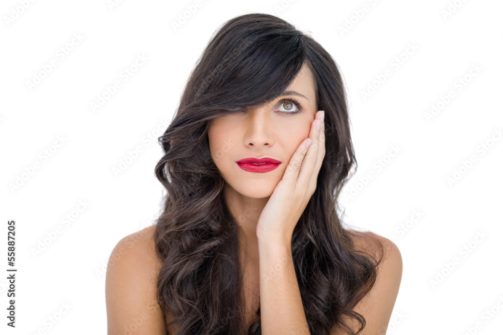 Sensual brunette with red lips touching her cheek looking up