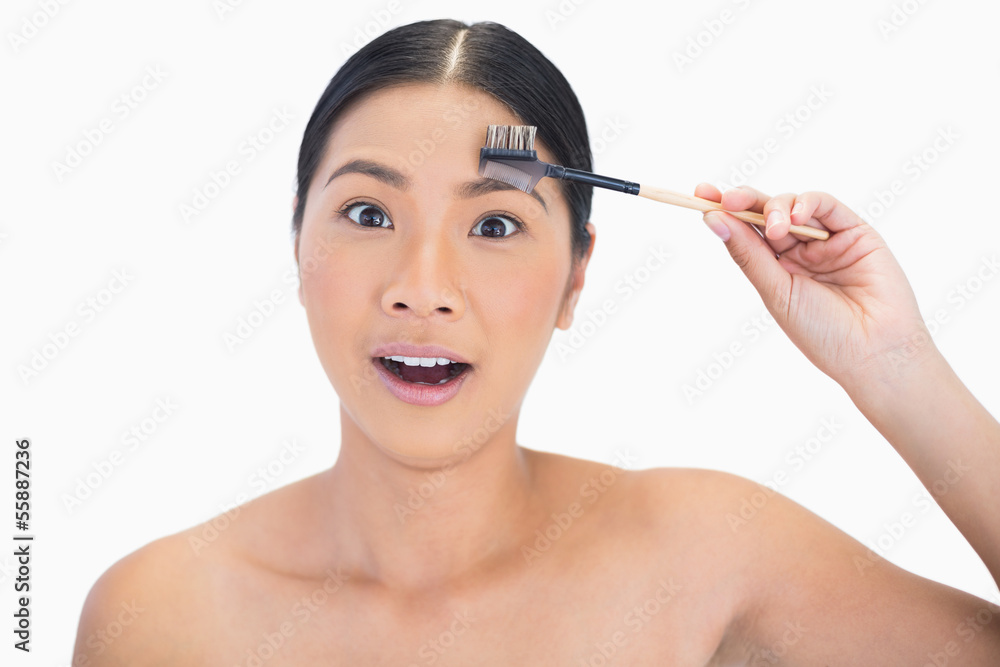 Fototapeta premium Astonished gorgeous natural model using eyebrow brush