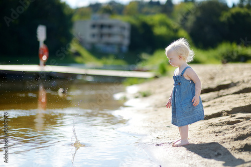 Adorable girl throwing stones into river