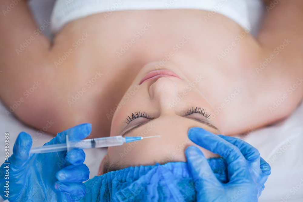 Surgeon making injection on woman lying Surgeon making injection on woman lying