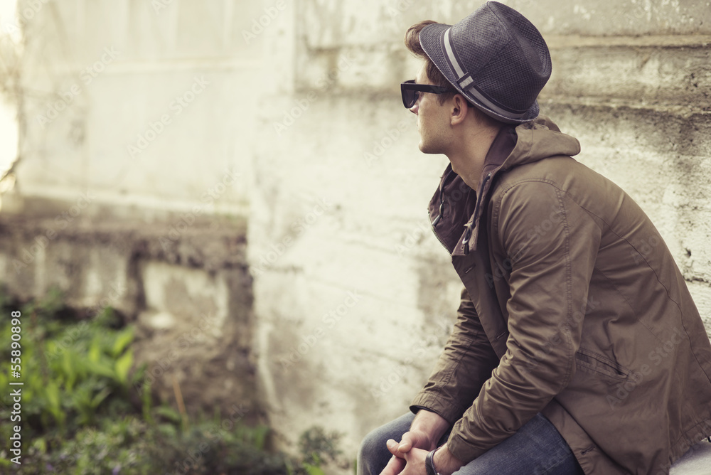Obraz premium Fashionable guy sitting on a background of an old wall