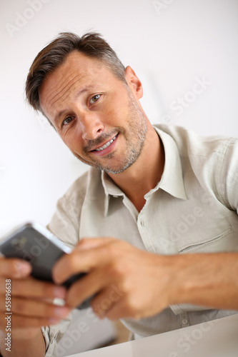 Smiling guy sending message with smartphone
