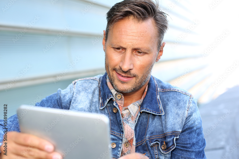 Man with blue jeans jacket using digital tablet