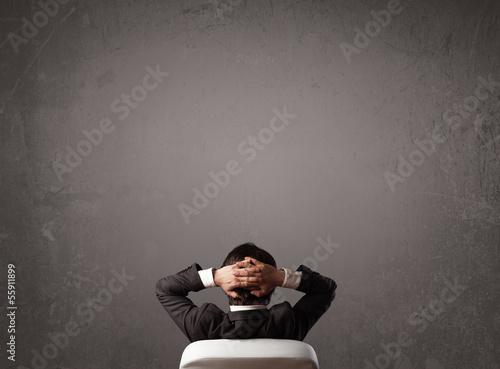 Businessman sitting in front of a wall with copy space