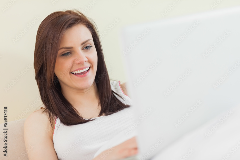 Laughing girl looking and using a laptop lying on a bed Laughing girl looking and using a laptop lying on a bed