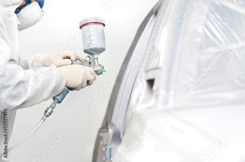 worker painting a white car in a special garage