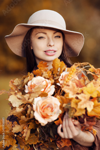 Young woman walking in autumn park with a bouquet of fall leav