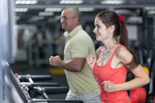 Sportive woman and man are jogging treadmill