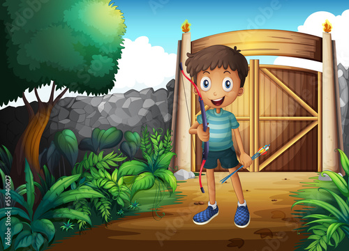 A boy inside the gated yard with a bow and arrow