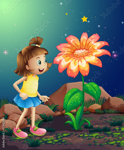 A little girl amazed by the giant flower near the rocks