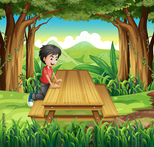 A boy in the forest with a wooden table and bench
