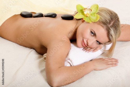 Woman relaxing with flower and hot stones