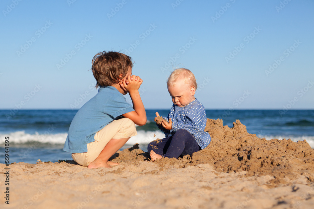 Brother and sister playing in sand at beach Brother and sister playing in sand at beach