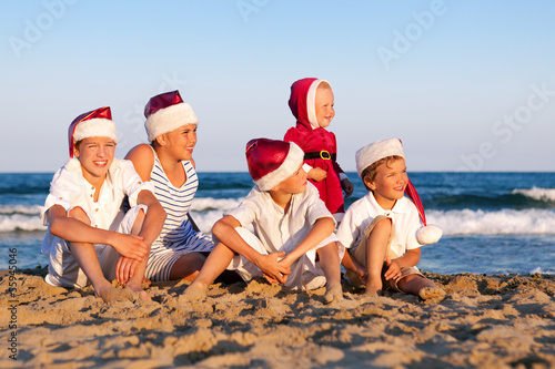 Children in santa claus hat are standing on beach