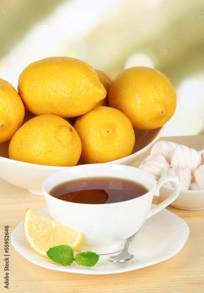 Cup of tea with lemon on table on light background Cup of tea with lemon on table on light background