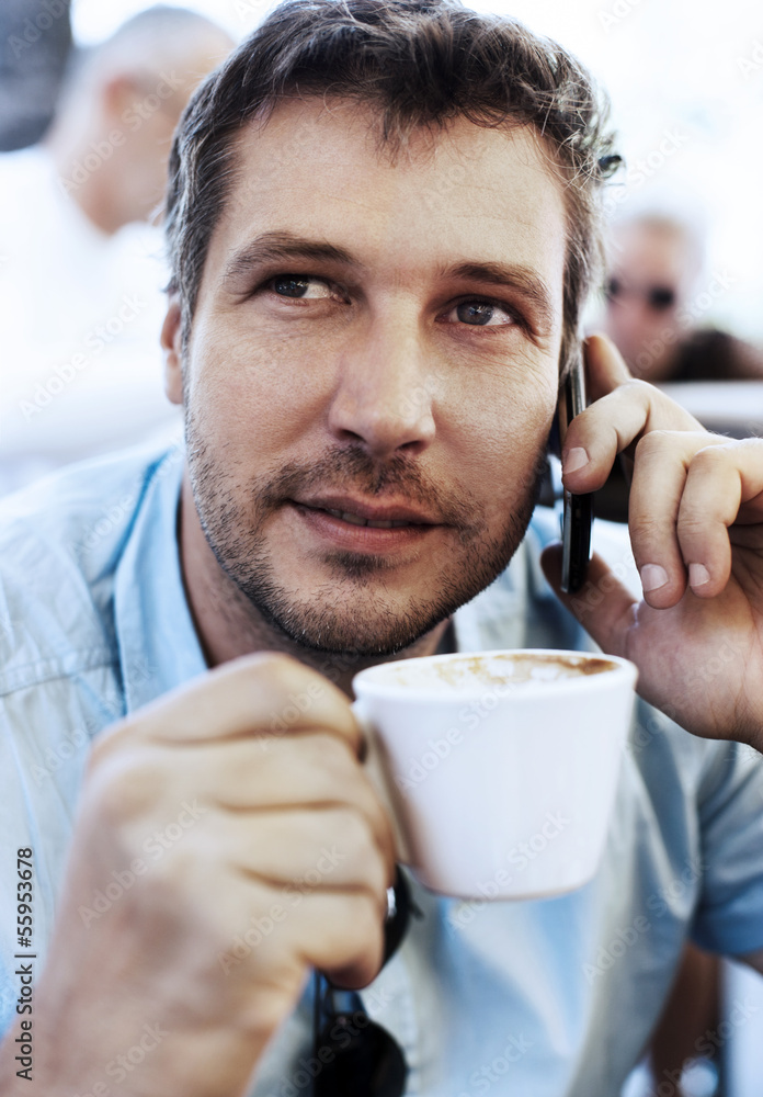 Young businessman talking on the phone and drinking coffee Young businessman talking on the phone and drinking coffee