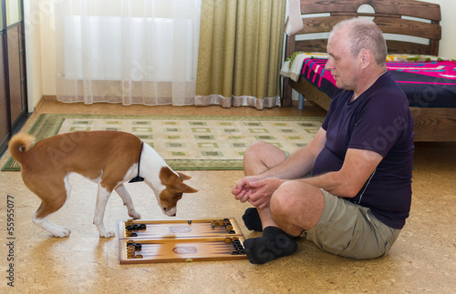 Young dog and mature man playing backgammon