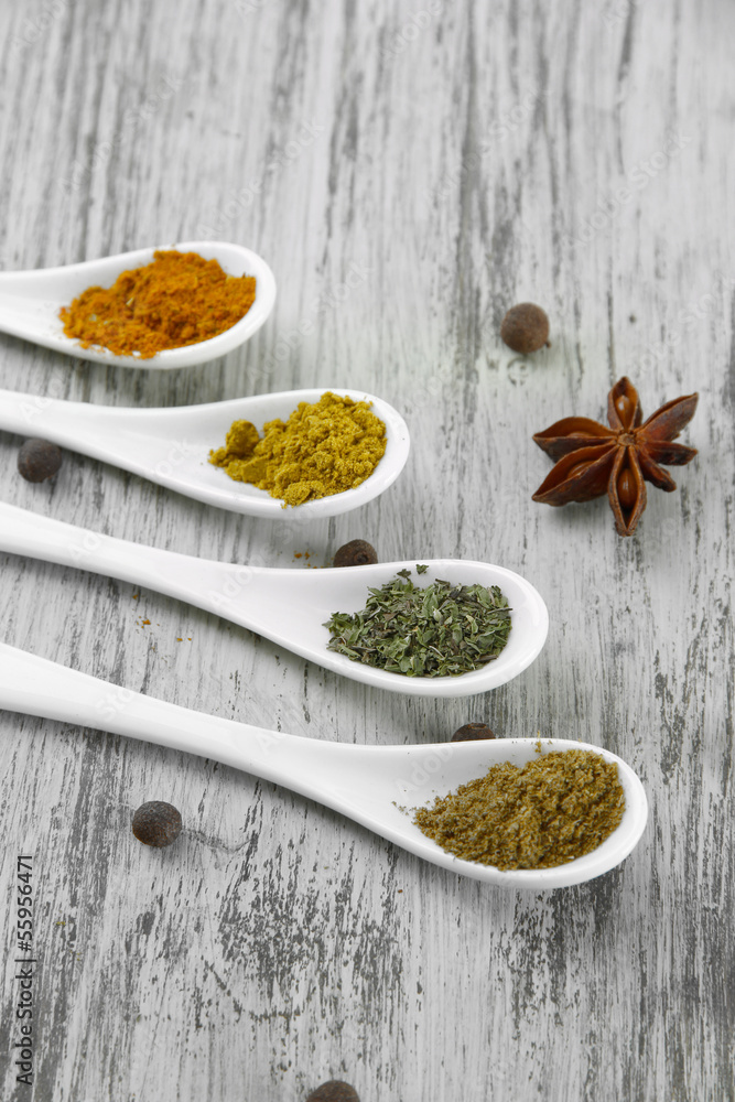 Assortment of spices in white spoons, on wooden background Assortment of spices in white spoons, on wooden background
