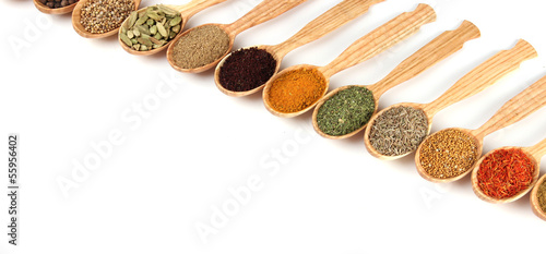 Assortment of spices in wooden spoons, isolated on white