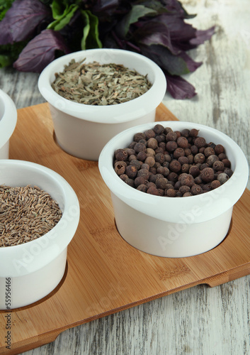 Assortment of spices in white bowls, on wooden background