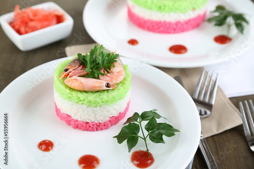 Colored rice on plates on napkins on wooden table