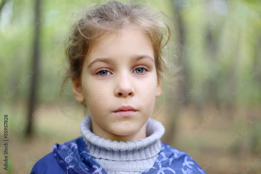 Serious little caucasian girl looks at distance in autumn forest Serious little caucasian girl looks at distance in autumn forest