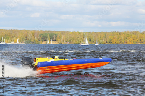 Sportsman fast at power boat on river at competitions in fall.