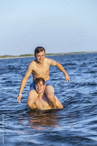  boys have fun playing piggyback in the ocean