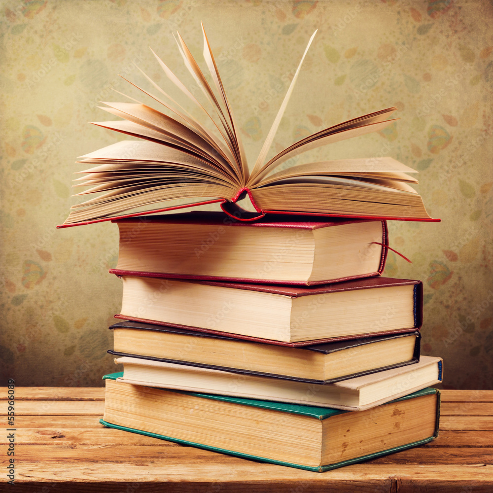 Fototapeta premium Vintage old books on wooden table over retro wallpaper
