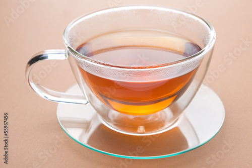 transparent cup of black tea on a brown background