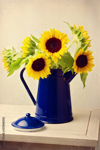 Fototapeta Naklejka Na Ścianę i Meble -  Sunflower bouquet in blue jug on wooden white table