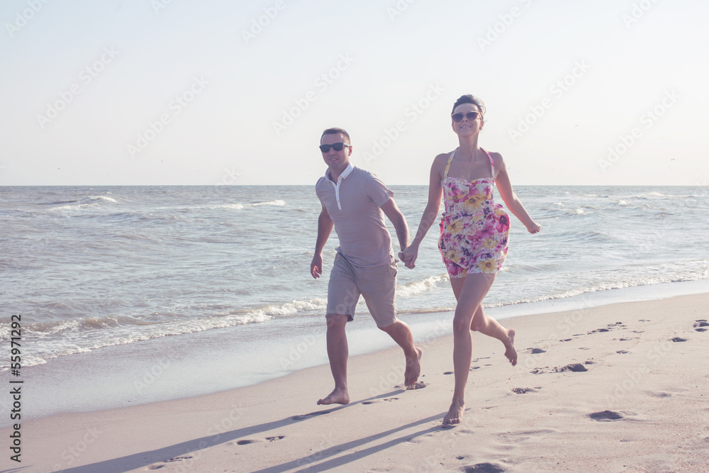 Young happy couple running together among a seashore